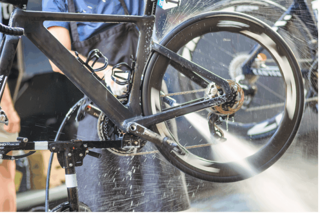 A man cleaning his electric bike wheel with a water spray machine