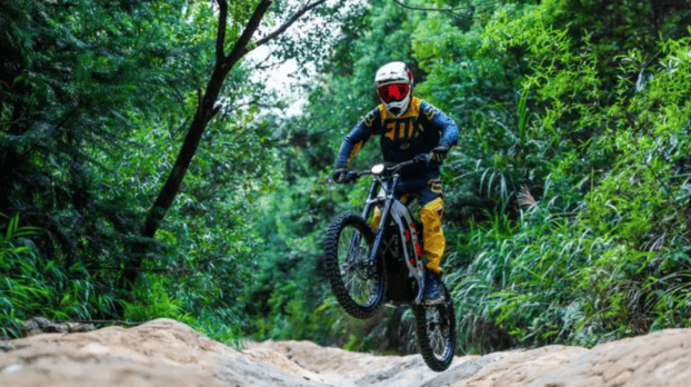A man riding a Surron electric bike over a  track.